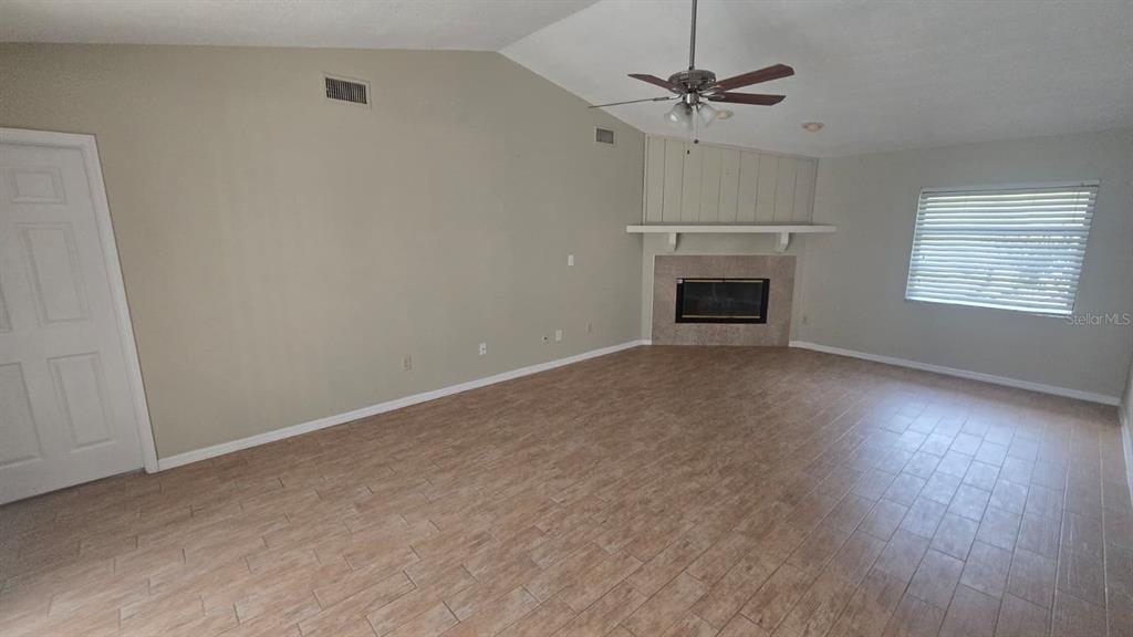 A living room features vaulted ceilings, tile flooring, and a corner fireplace with a mantel — 5461 OAKRIDGE DRIVE, PALM HARBOR, FL
