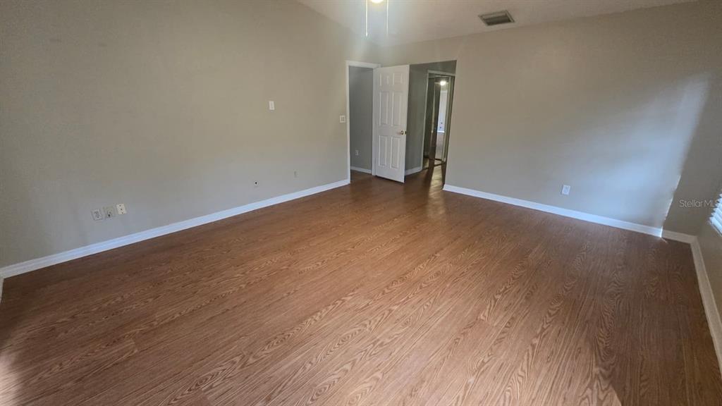 An empty room with light-colored walls, wood-look flooring, and an open doorway — 5461 OAKRIDGE DRIVE, PALM HARBOR, FL