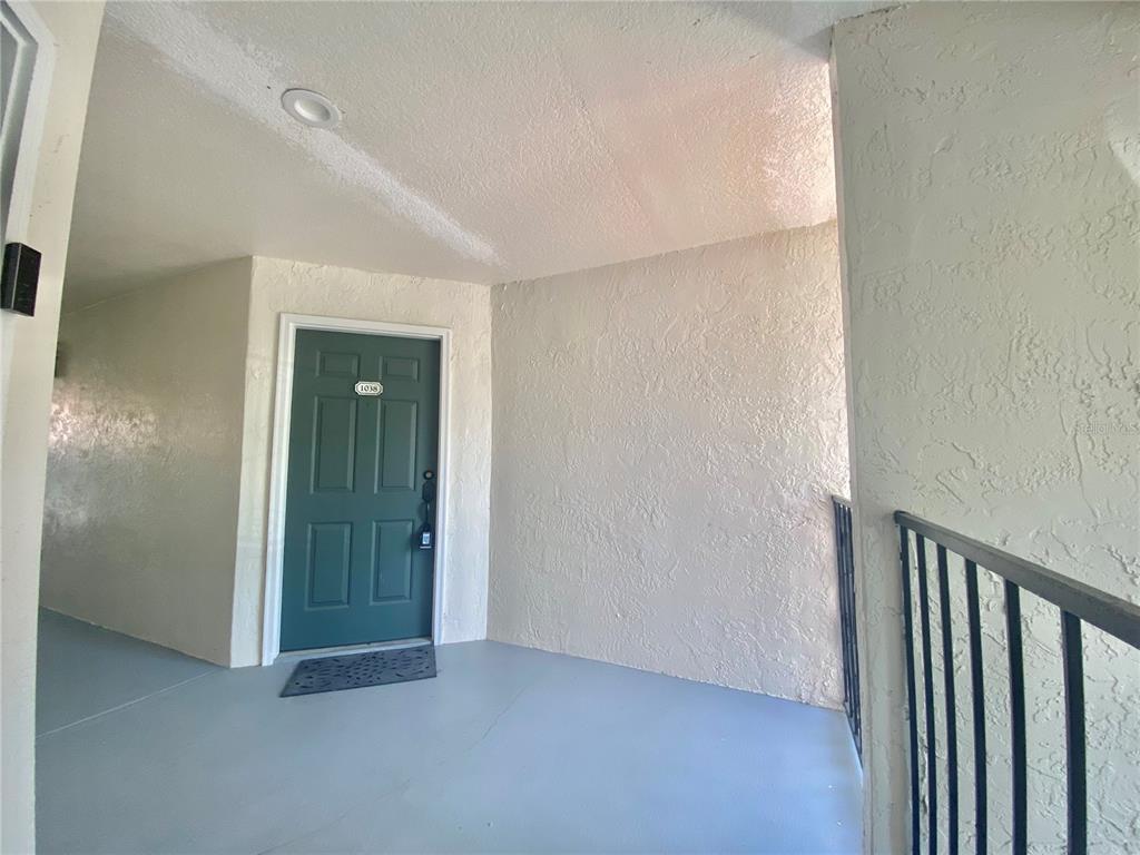 A green front door with the number 1038 is set in a textured, light-colored wall — 5144 CONROY ROAD UNIT 38, ORLANDO, FL