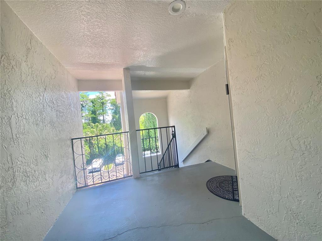 An outdoor covered landing features a gray floor, wrought iron railings, and a welcome mat — 5144 CONROY ROAD UNIT 38, ORLANDO, FL