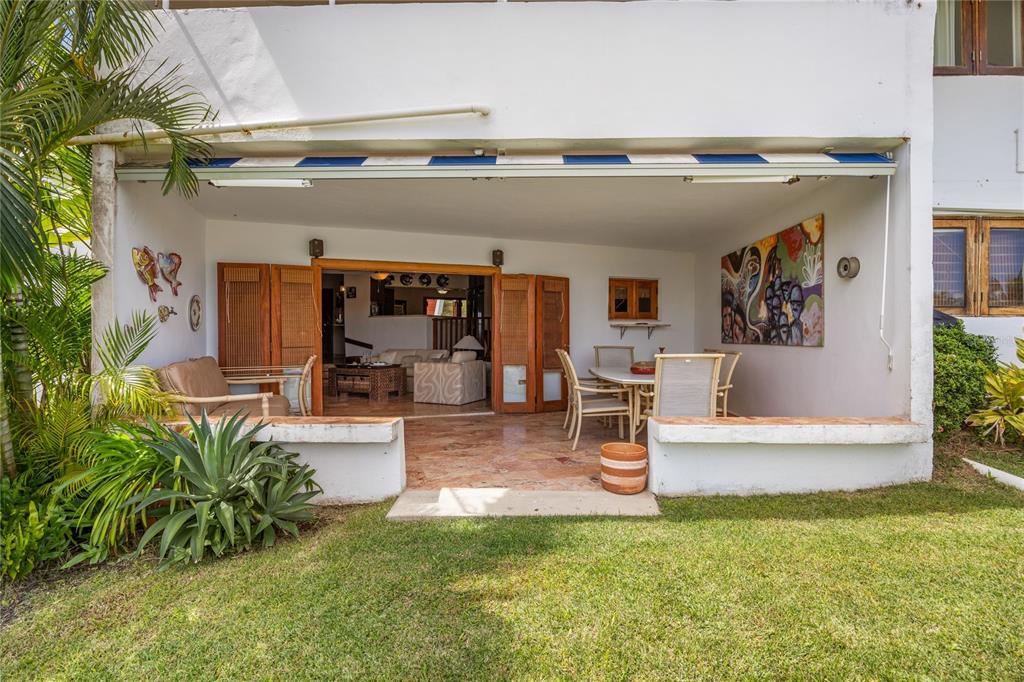 A covered patio with tile flooring opens into a living area with wooden folding doors — RIO MAR CLUSTER 3, VILLA DEL AMANECER, RIO GRANDE, PR