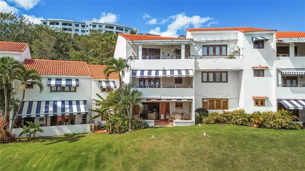 A multi-story white stucco building with red tile roofs and blue-and-white striped awnings — RIO MAR CLUSTER 3, VILLA DEL AMANECER, RIO GRANDE, PR