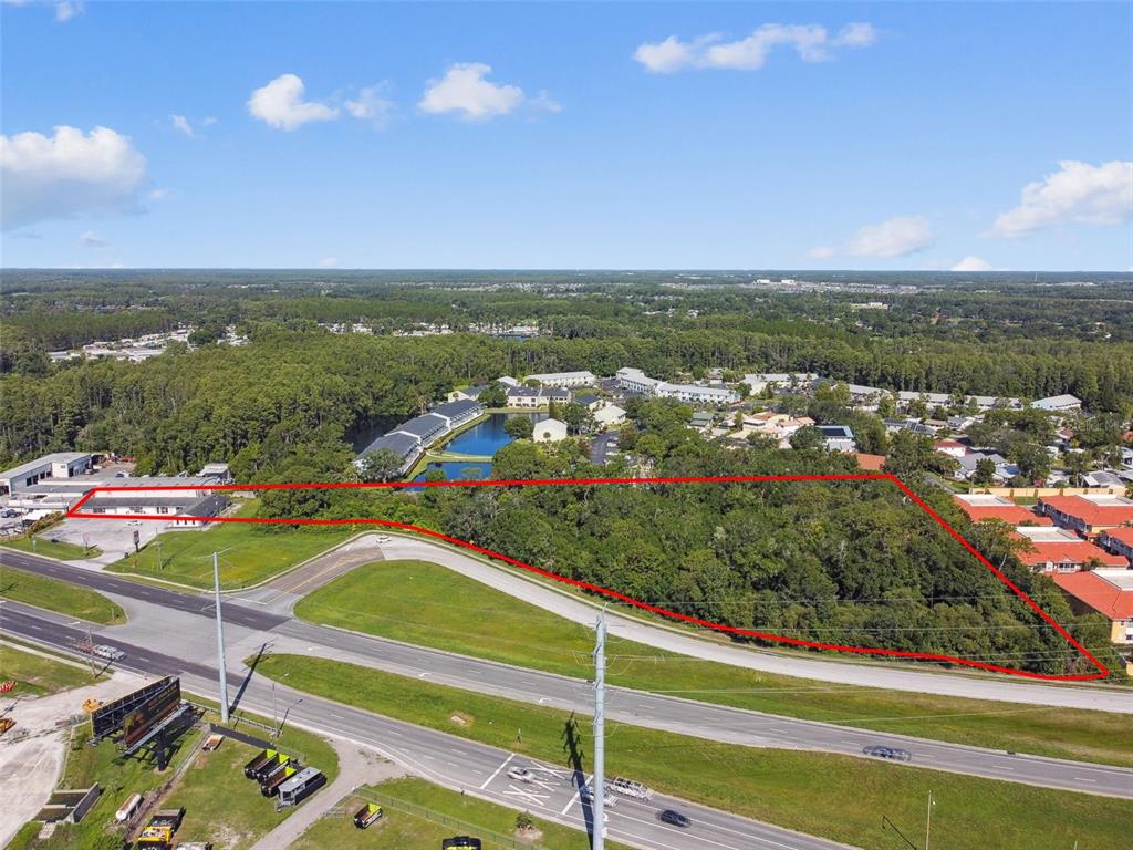 An aerial view shows a vacant, wooded lot outlined in red next to a highway — 1703 DALE MABRY HIGHWAY, LUTZ, FL