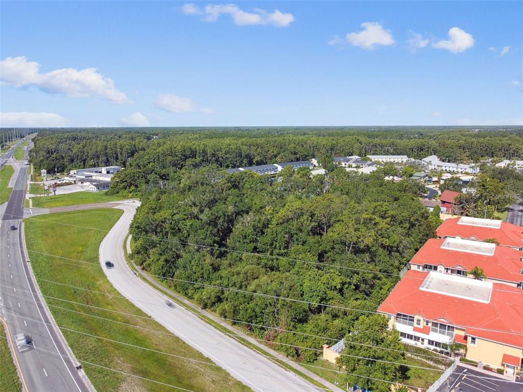 An aerial view shows a wooded lot bordered by a road and residential buildings — 1703 DALE MABRY HIGHWAY, LUTZ, FL