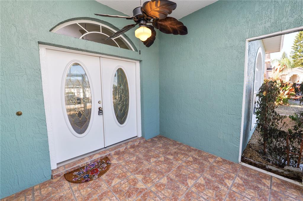 A covered entryway features a tiled floor, teal stucco walls, and a double front door — 2258 COLONY CLUB DRIVE, LAKELAND, FL