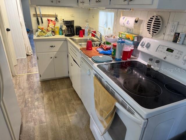 A kitchen features white cabinets, a black electric stove, and wood-look flooring — 620 49TH AVENUE W, BRADENTON, FL