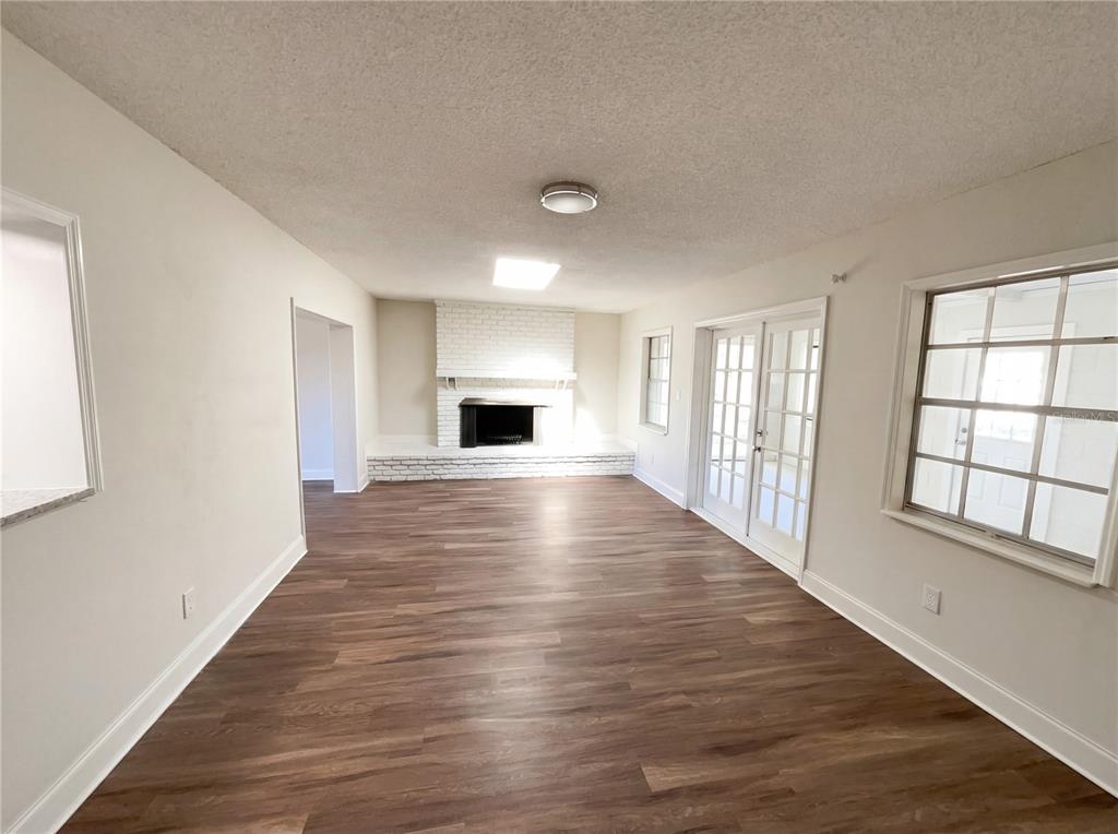A living room with wood-look flooring, a white brick fireplace, and French doors — 2052 LEANNE COURT, WINTER PARK, FL