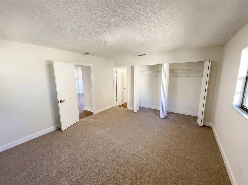 A bedroom with beige carpet, white walls, a closet with folding doors, and two doorways — 2052 LEANNE COURT, WINTER PARK, FL