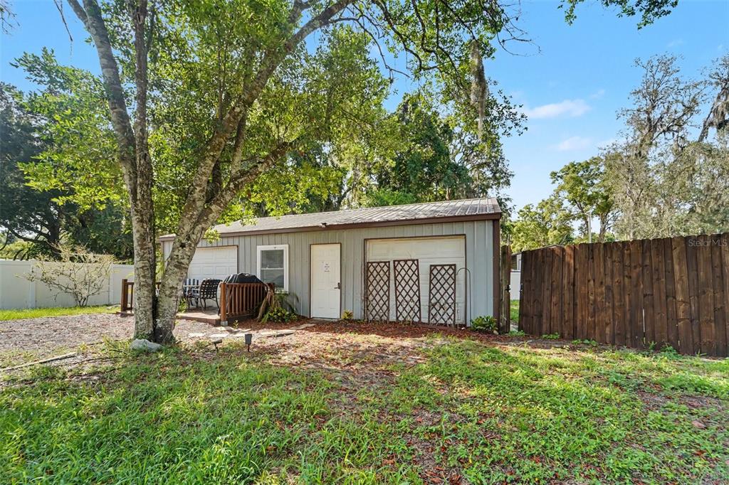 A detached garage with a side door, a small deck, and a wooden privacy fence — 12464 LANTANA AVENUE, NEW PORT RICHEY, FL