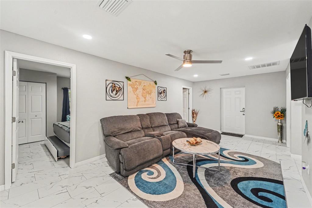 A living room features gray tile floors, a sectional sofa, and a patterned area rug — 12464 LANTANA AVENUE, NEW PORT RICHEY, FL
