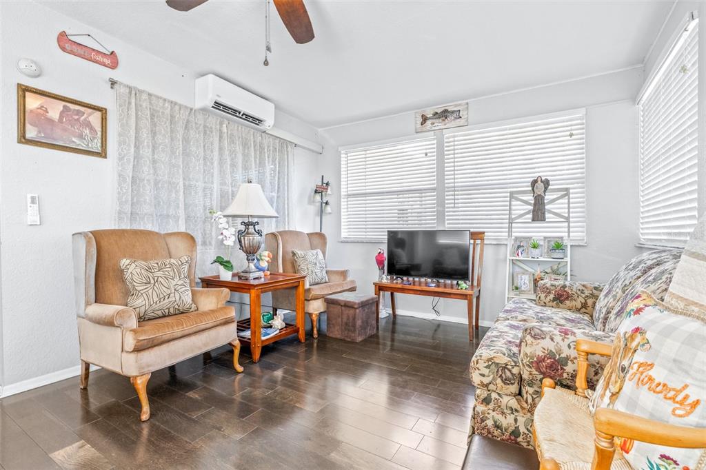 A living room features two tan armchairs, a floral sofa, and dark wood flooring — 4742 CYPRESS DRIVE, LAKE WALES, FL