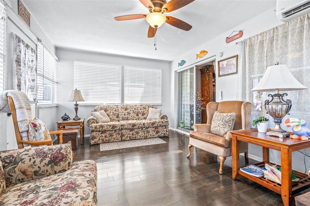 A living room features floral sofas, a wingback chair, dark wood flooring, and a ceiling fan — 4742 CYPRESS DRIVE, LAKE WALES, FL