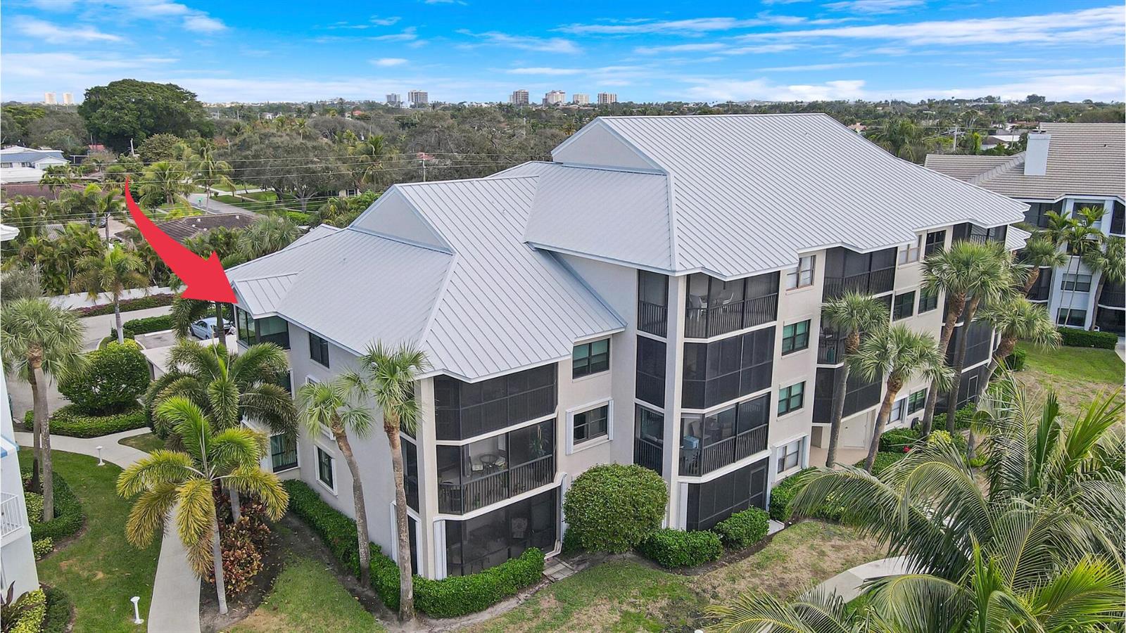 An aerial view of a multi-story residential building with a metal roof and screened balconies — 235 Bay Colony Drive N, Juno Beach FL 33408, JUNO BEACH, FL