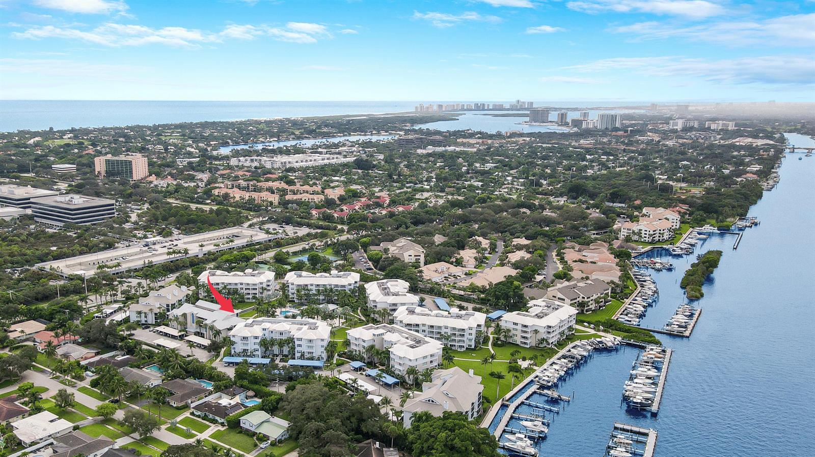 An aerial view shows a waterfront condominium complex with a red arrow pointing to a building — 235 Bay Colony Drive N, Juno Beach FL 33408, JUNO BEACH, FL