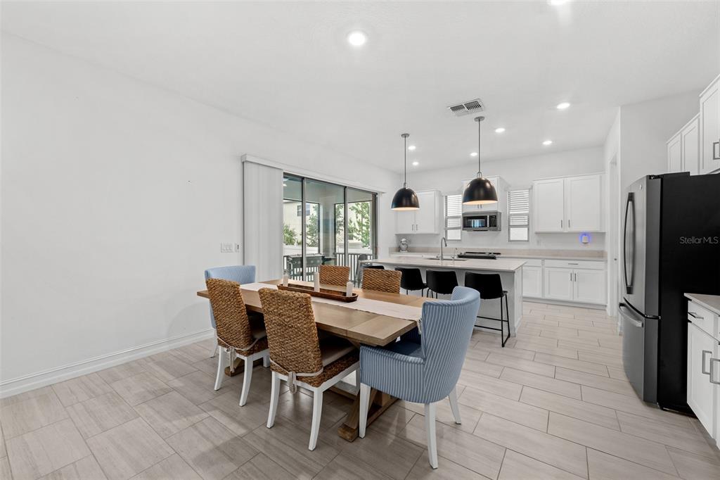 A dining area with a wooden table and chairs sits adjacent to a modern kitchen — 7711 S SWOOPE STREET, TAMPA, FL