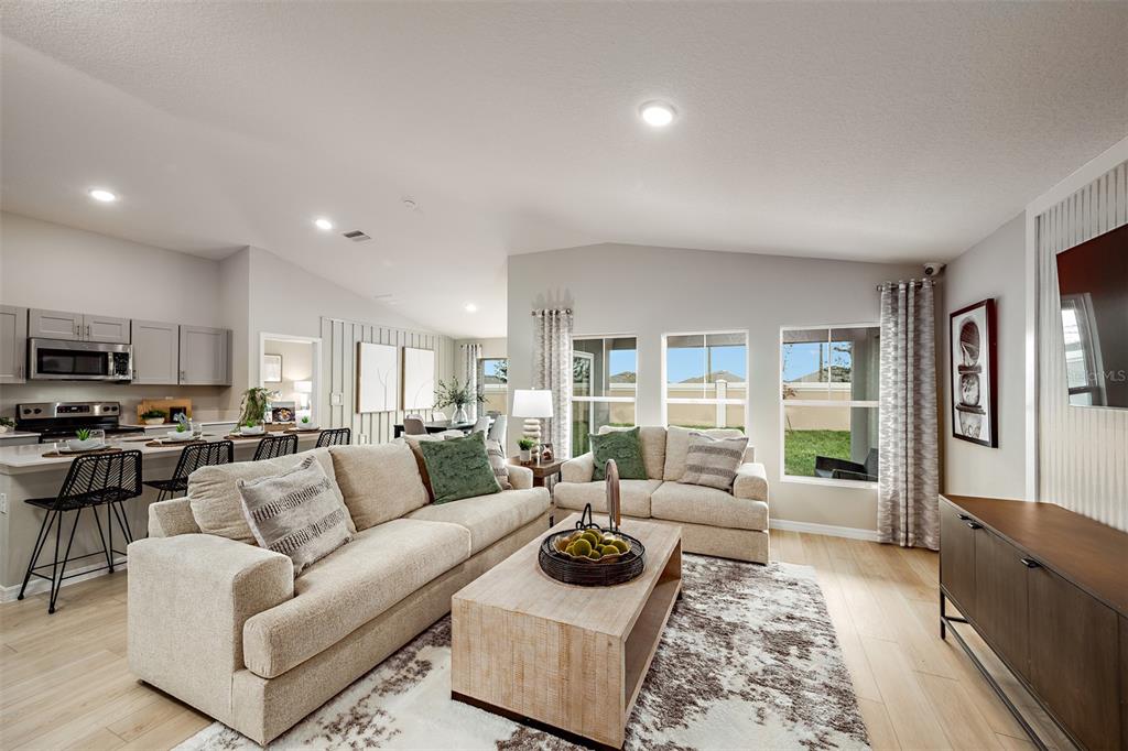 A living room with light-colored sofas, a wooden coffee table, and an open kitchen — 34987 ARBOR RETREAT DRIVE, DADE CITY, FL