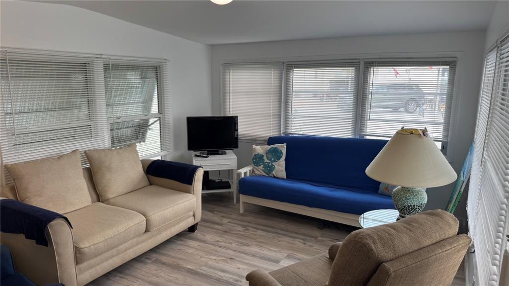 A living room features a beige sofa, a blue futon, a television, and wood-look flooring — 1704 PENNSYLVANIA AVENUE, BRADENTON, FL