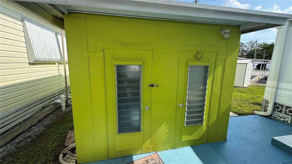 A lime green exterior shed features two doors with louvered glass windows — 1704 PENNSYLVANIA AVENUE, BRADENTON, FL