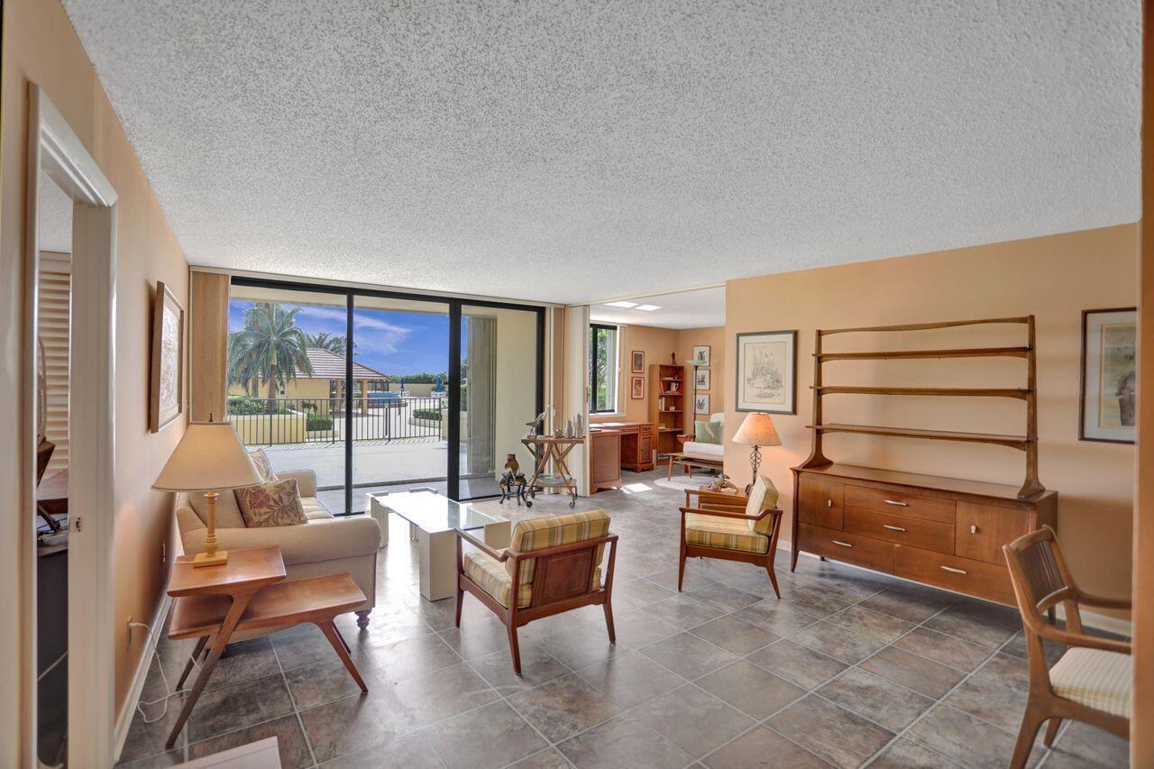 A living room with tile floors, mid-century furniture, and a sliding glass door to a patio — 100 Ocean Trail Way # 109, Jupiter FL 33477, JUPITER, FL