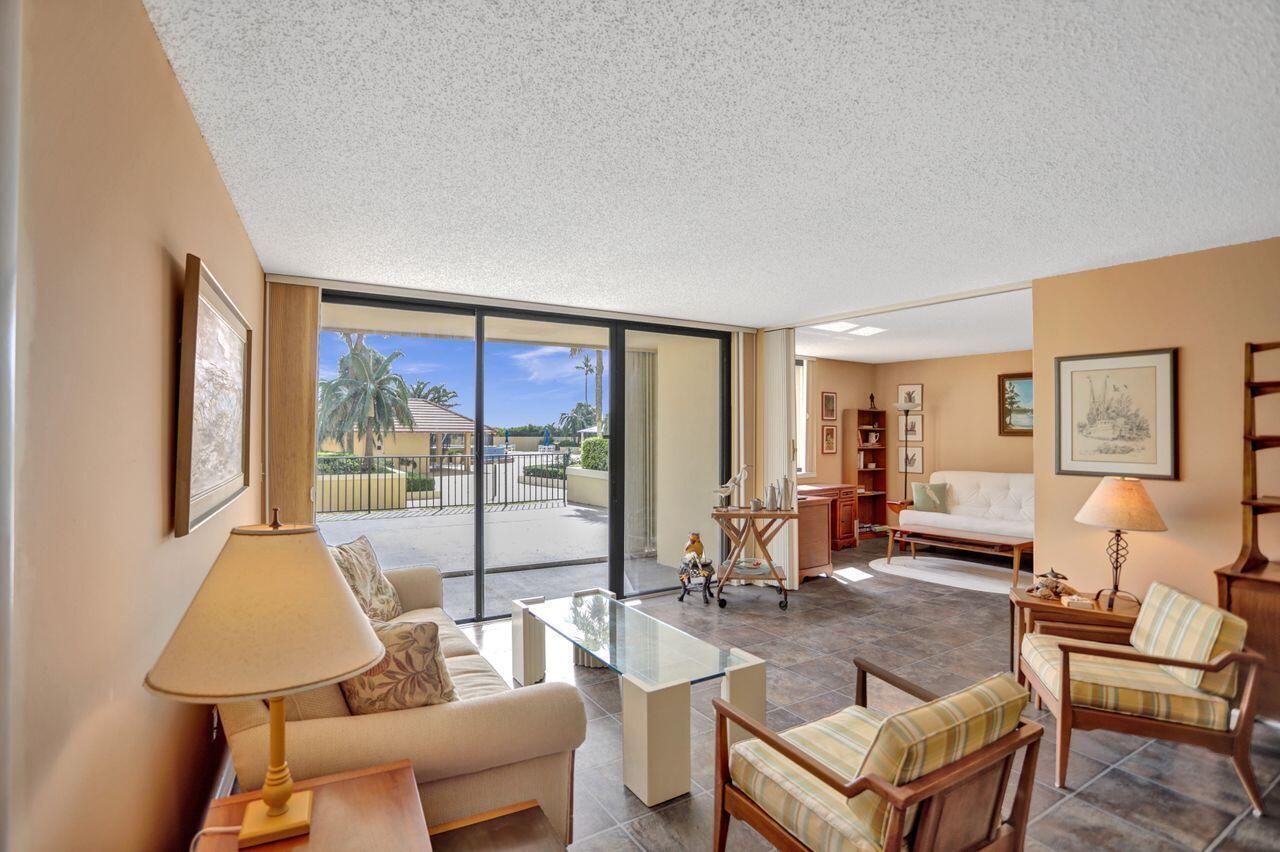 A living room with tile floors, a glass coffee table, and sliding doors to a patio — 100 Ocean Trail Way # 109, Jupiter FL 33477, JUPITER, FL