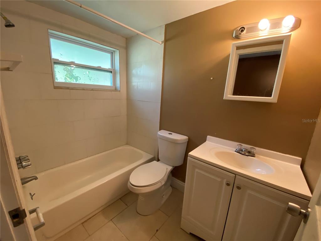 A bathroom features a white vanity, a toilet, and a bathtub with white wall tiles — 1609 E 143RD AVENUE UNIT 105-108, TAMPA, FL