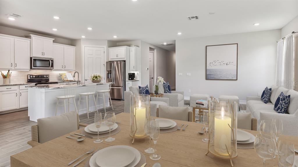 A dining area in the foreground opens to a kitchen and living room with neutral decor — 12769 SEAGRASS DRIVE, PUNTA GORDA, FL