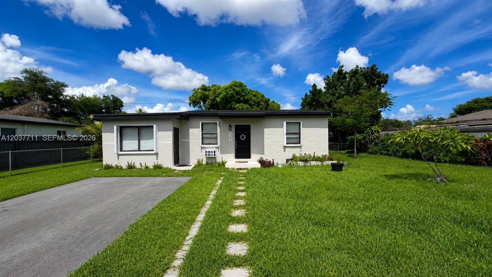 A single-story house with a black front door, a driveway, and a grassy lawn — 17981 NW 3rd Ave, Miami Gardens FL 33169, MIAMI GARDENS, FL