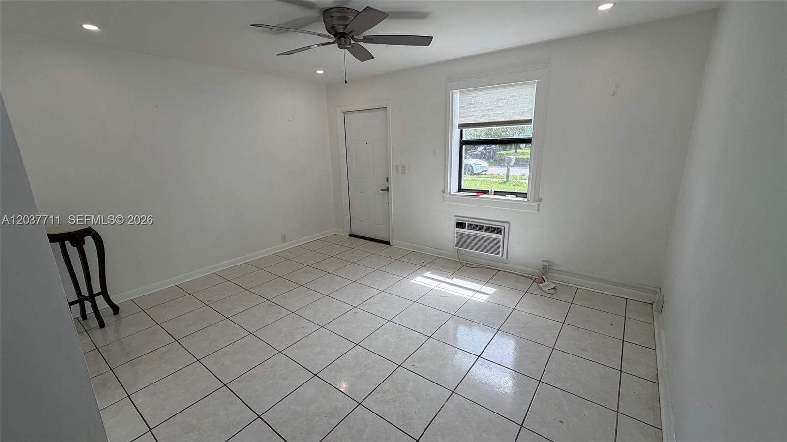 An empty room features white walls, light-colored tile flooring, a ceiling fan, and a window — 17981 NW 3rd Ave, Miami Gardens FL 33169, MIAMI GARDENS, FL