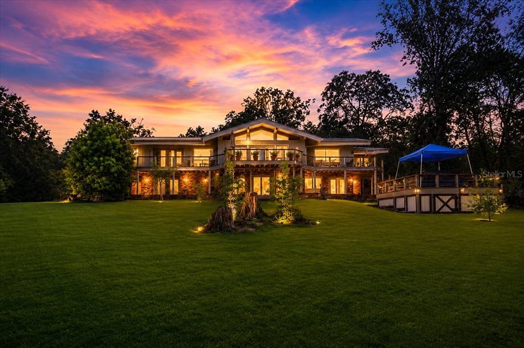 A two-story house with a large deck and lawn sits under a vibrant sunset sky — 5278 SW COUNTY ROAD 138, FORT WHITE, FL