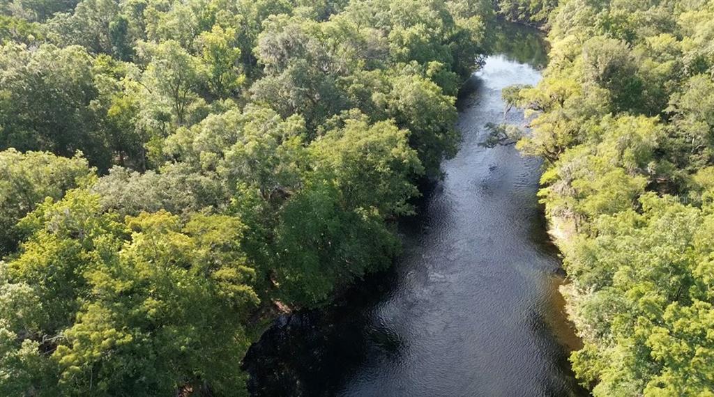 An aerial view shows a narrow river flowing through a dense, green forest — 5278 SW COUNTY ROAD 138, FORT WHITE, FL