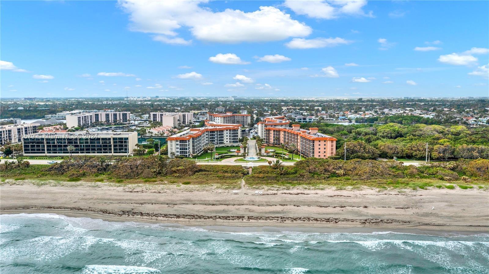 An aerial view shows beachfront apartment buildings with orange roofs surrounded by trees and water — 2871 N Ocean Boulevard # C417, Boca Raton FL 33431, BOCA RATON, FL
