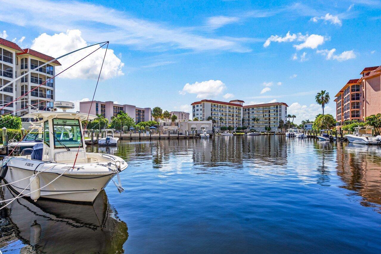 A white motorboat is docked in a canal surrounded by multi-story residential apartment buildings — 2871 N Ocean Boulevard # C417, Boca Raton FL 33431, BOCA RATON, FL