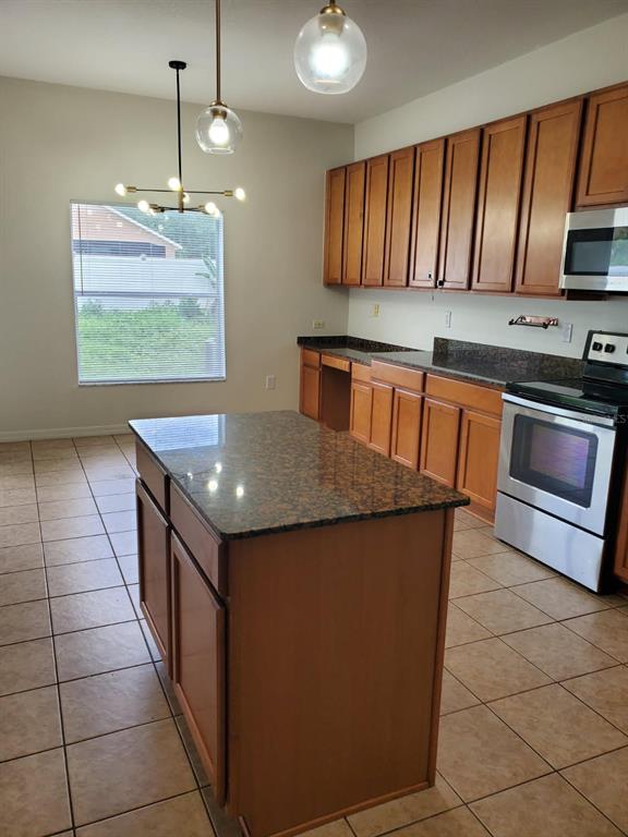 A kitchen features wood cabinets, granite countertops, a center island, and stainless steel appliances — 12148 LUFTBURROW LANE, HUDSON, FL