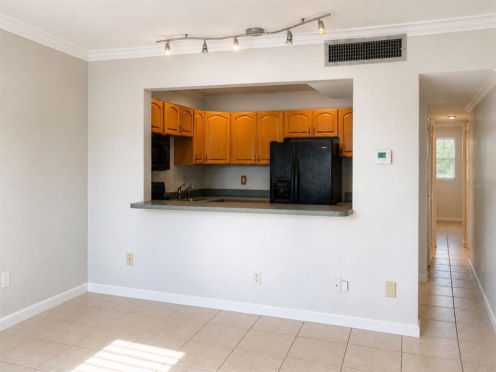 A kitchen with wood cabinets and black appliances is visible through a pass-through opening — 2500 HARN BOULEVARD UNIT F24, CLEARWATER, FL