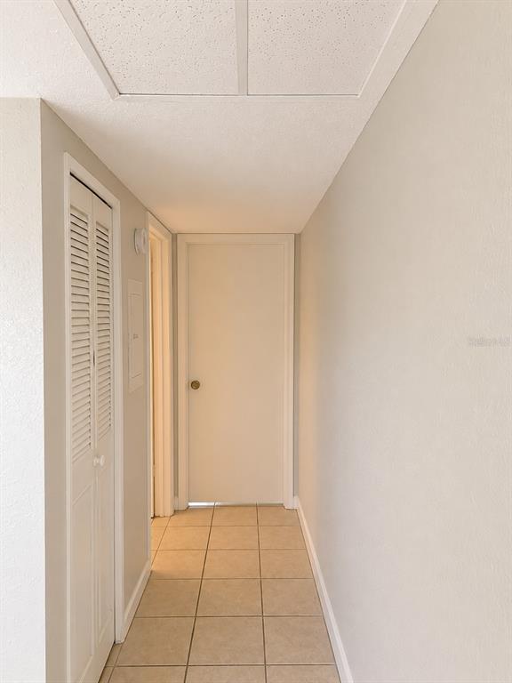 A hallway features light-colored tile flooring, white walls, a louvered closet door, and a closed door — 2500 HARN BOULEVARD UNIT F24, CLEARWATER, FL