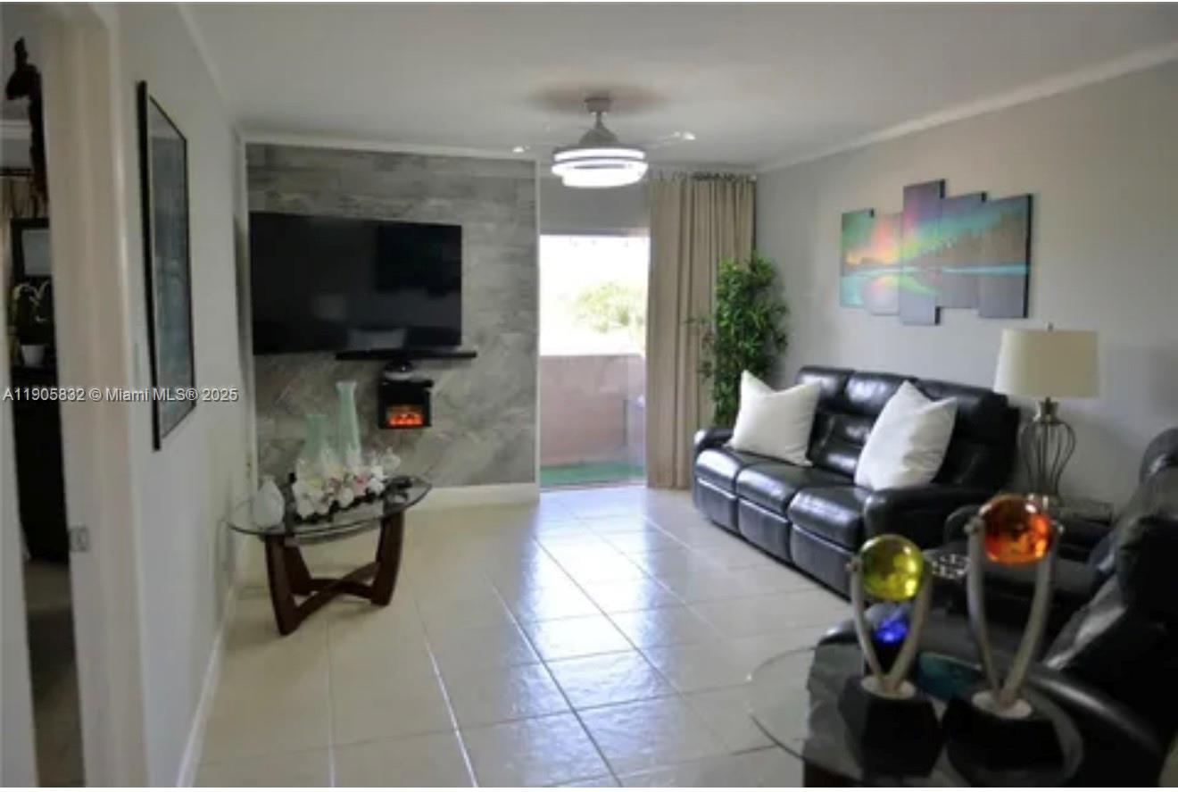 A living room features a stone-accented wall with a mounted television and tiled flooring — 10900 SW 104th St # 314, Miami FL 33176, MIAMI, FL