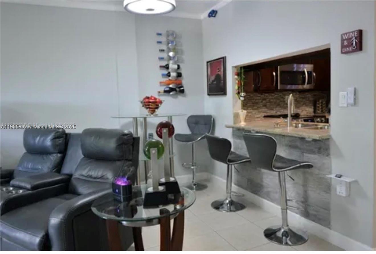 A living room features a glass-topped table, bar stools, and a wall-mounted wine rack — 10900 SW 104th St # 314, Miami FL 33176, MIAMI, FL