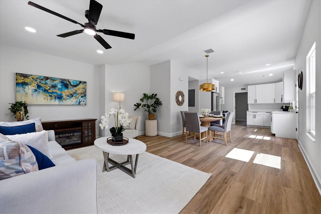 An open-concept living and dining area features light wood flooring, white cabinetry, and a ceiling fan — 7206 RHODE ISLAND DRIVE, TAMPA, FL