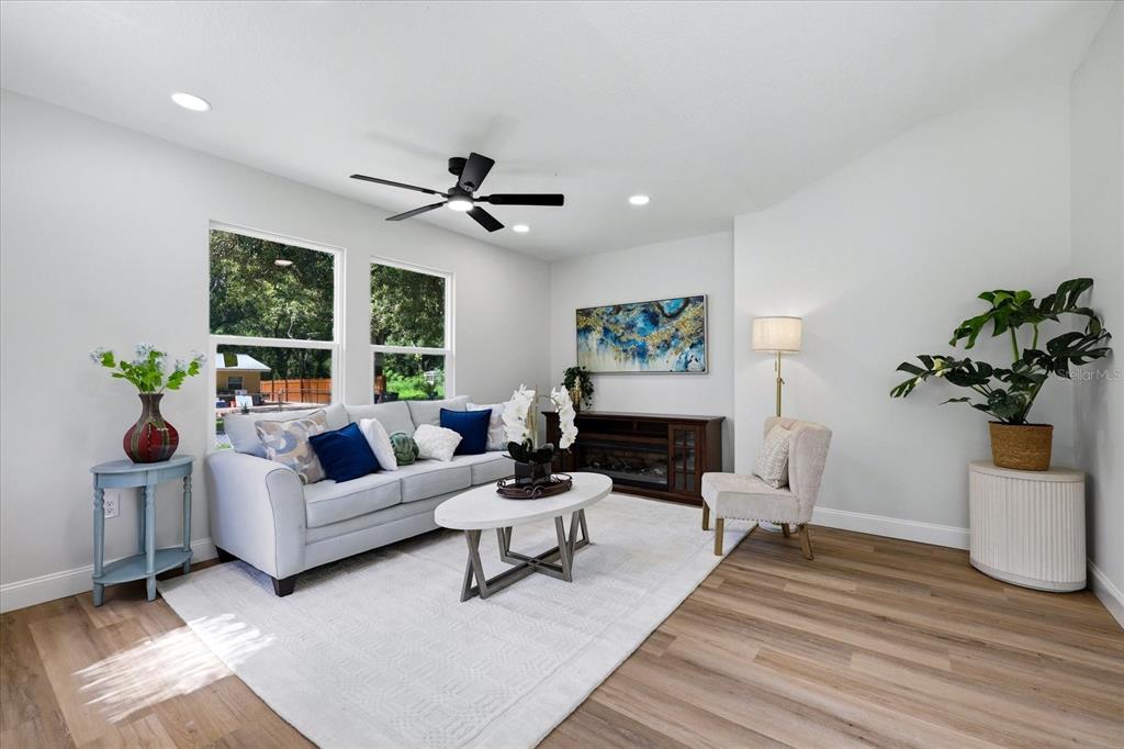 A living room features light wood floors, a grey sofa, and a white area rug — 7206 RHODE ISLAND DRIVE, TAMPA, FL
