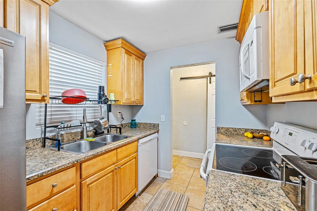 A kitchen features light wood cabinets, granite countertops, stainless steel appliances, and tile flooring — 2821 OAK LEA DRIVE, SOUTH DAYTONA, FL