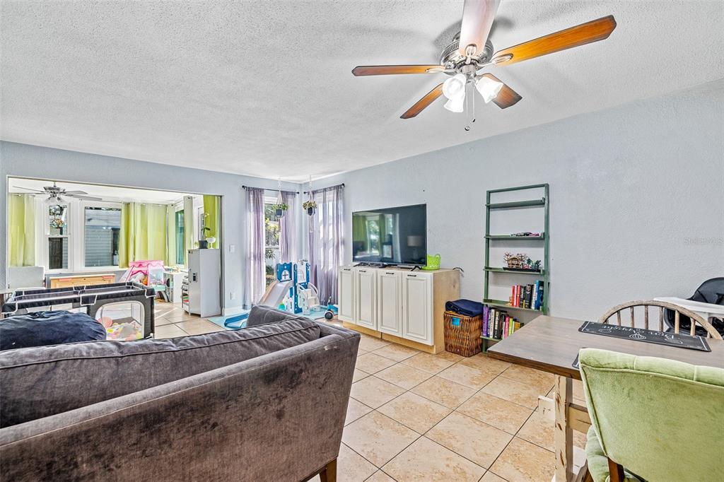 A living room with tile floors, a ceiling fan, a television, and a dining area — 2821 OAK LEA DRIVE, SOUTH DAYTONA, FL