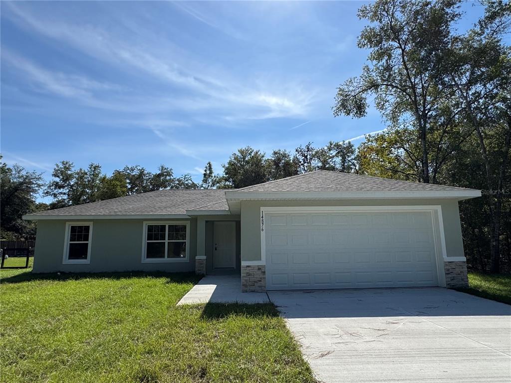 A single-story house with a light green exterior, a two-car garage, and a concrete driveway — 17603 SW 112TH LANE, DUNNELLON, FL
