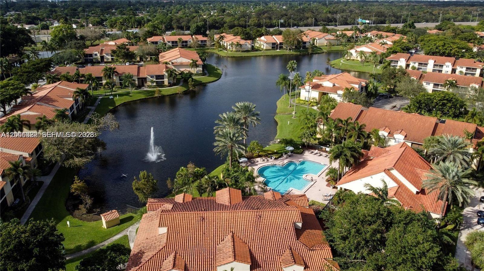 An aerial view shows a residential complex with red-tiled roofs, a lake, and a pool — 1227 SW 46th Ave # 304, Pompano Beach FL 33069, POMPANO BEACH, FL