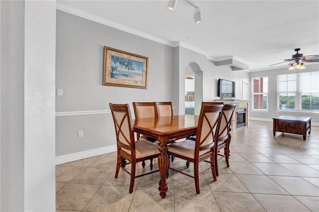 A dining area with a wooden table and chairs sits on tiled floors — 2731 VIA CAPRI UNIT 928, CLEARWATER, FL