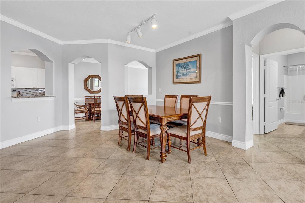 A dining room with a wooden table, six chairs, tile flooring, and arched wall openings — 2731 VIA CAPRI UNIT 928, CLEARWATER, FL