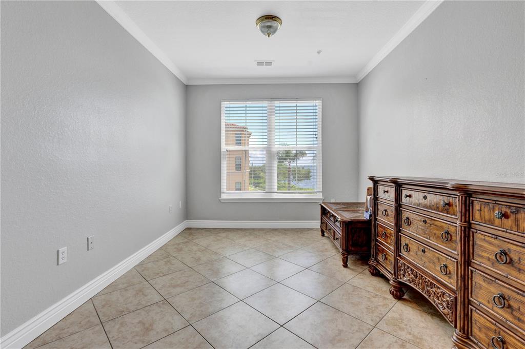 A room with light gray walls, tile flooring, a window, and a wooden dresser — 2731 VIA CAPRI UNIT 928, CLEARWATER, FL