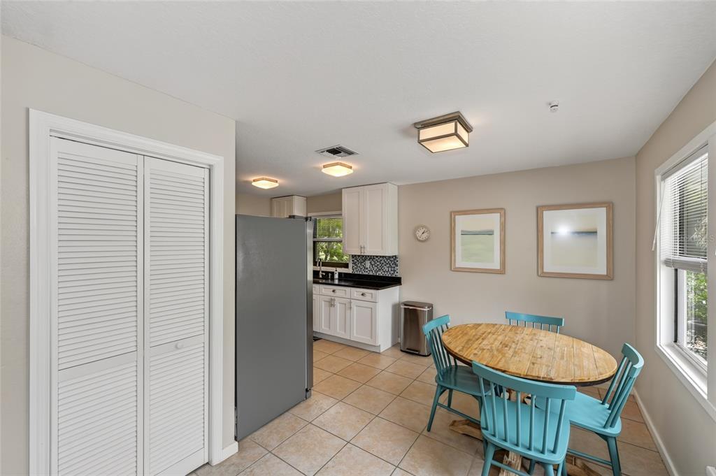 A kitchen and dining area with white cabinets, tile flooring, and a round wooden table — 2475 ALAMEDA AVENUE UNIT B, SARASOTA, FL