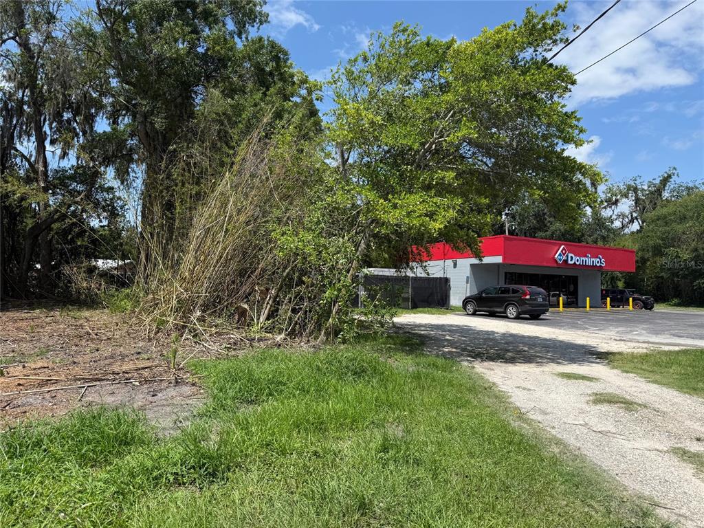A Domino's restaurant stands next to a vacant, grassy lot with trees — 661 W MADISON STREET, STARKE, FL