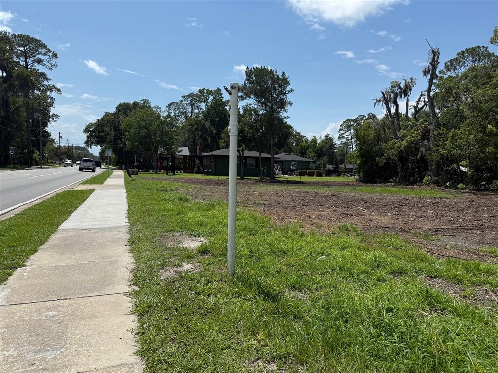 A vacant, cleared lot sits next to a sidewalk and a road with trees nearby — 661 W MADISON STREET, STARKE, FL