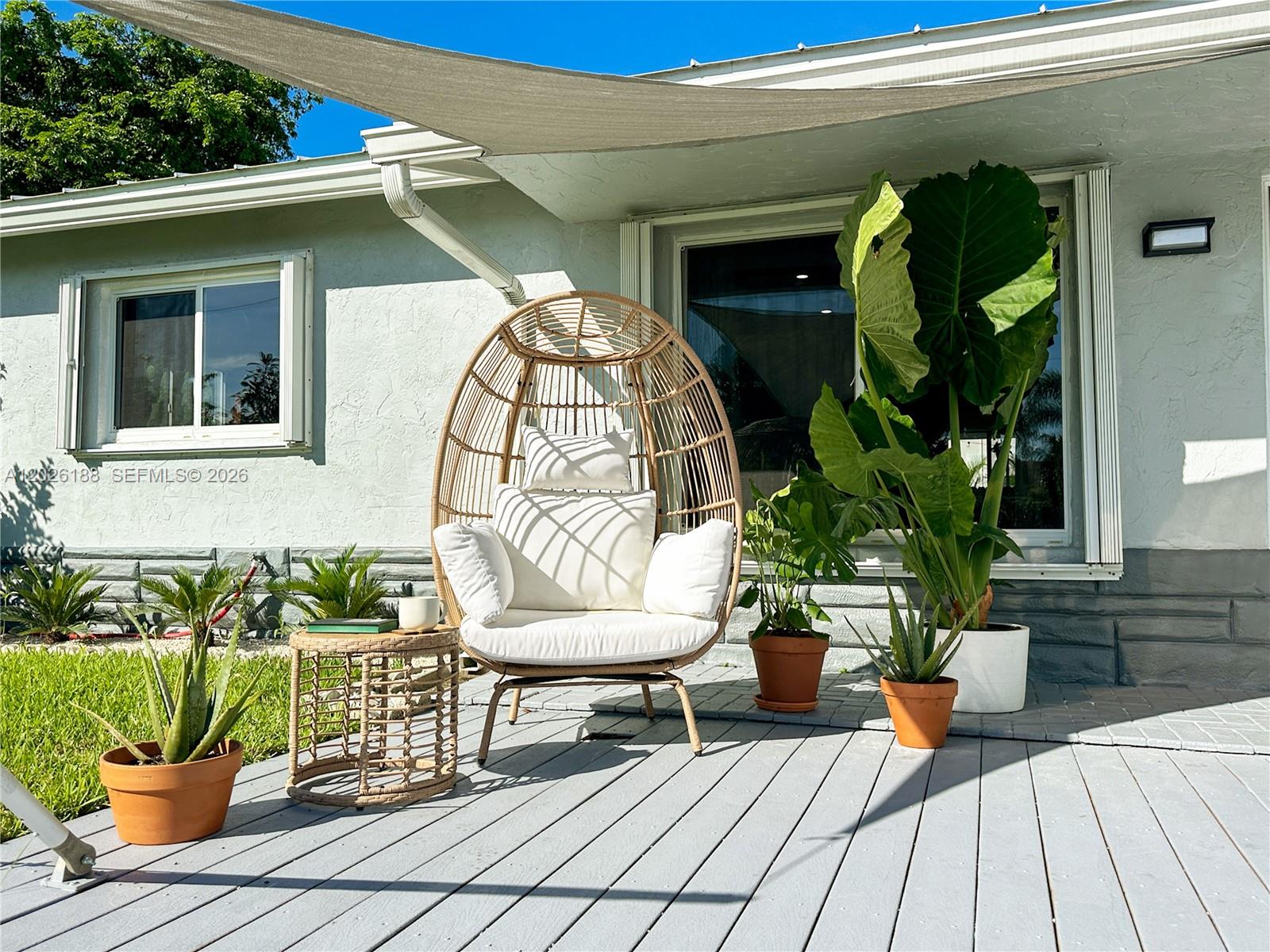 A patio with a wicker egg chair, potted plants, and a shade sail — 191 SE 13th Ave, Pompano Beach FL 33060, POMPANO BEACH, FL